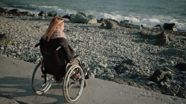 La-mujer-con-discapacidad-está-sentada-en-un-carruaje-no-válido-y-mirando-al-mar
