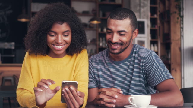 Young-couple-watching-video-on-mobile-phone-and-laughing