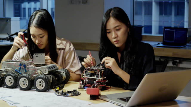 Asiatischer-junger-Elektronikingenieur,-der-Laptop-verwendet,-um-Informationen-zu-recherchieren,-um-Roboter-zusammen-zu-machen.-Technologie--und-Innovationskonzept.