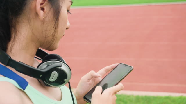 Lifestyle-asiatische-Sportfrauen-halten-Smartphone-spielen-Musik-Entspannung