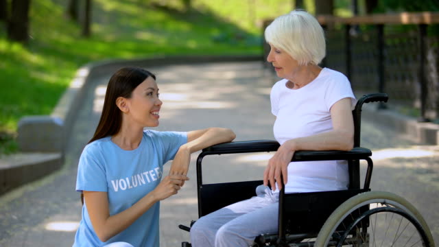 Disabled-senior-lady-in-wheelchair-talking-to-volunteer,-conversation-support