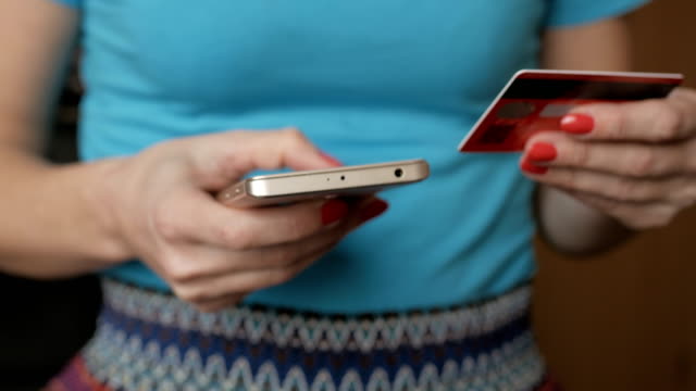 Frau-im-blauen-Hemd,-die-Online-Zahlung-mit-Kreditkarte-und-Smartphone,-Online-Shopping,-Lifestyle-Technologie.-Online-Banking-mit-Smartphone.-Mädchen-gibt-Bankkartennummer-in-Smartphone-ein.