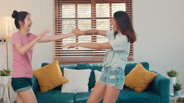 Asiatische-lesbische-Paar-tanzen,-singen,-Musik-hören,-während-im-Wohnzimmer.
