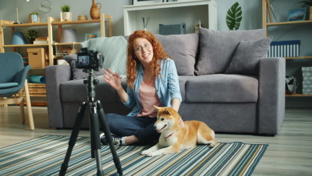 Nette-Teenager-Blogger-Aufnahme-Videoblog-sitzt-auf-dem-Boden-zu-Hause-mit-Haustier-Hund