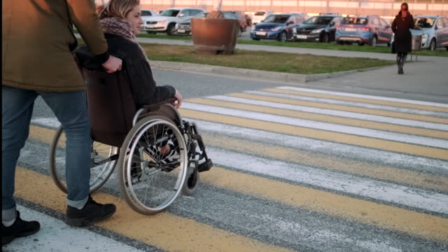 Mann-schiebt-den-Rollstuhl-mit-behinderter-Freundin-über-die-Straße