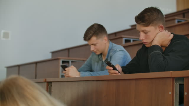 Grupo-multiétnico-de-estudiantes-que-utilizan-teléfonos-inteligentes-durante-la-conferencia.-Jóvenes-que-usan-las-redes-sociales-mientras-estudian-en-la-Universidad.