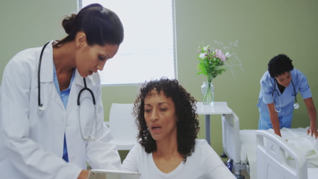 Front-view-of-African-american-female-doctor-discussing-medical-report-with-disabled-female-patient