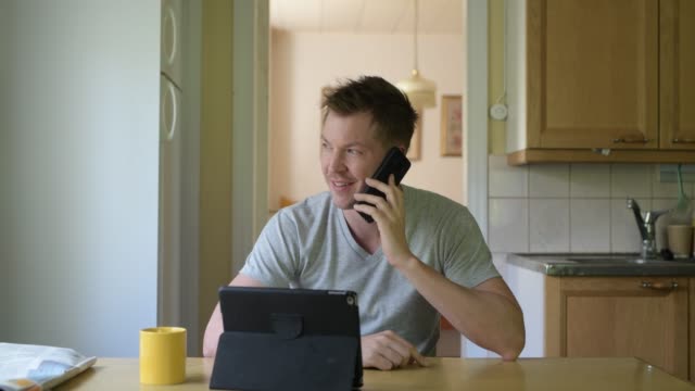Junge-glückliche-Mann-mit-digitalen-Tablet-und-Telefon-durch-das-Fenster