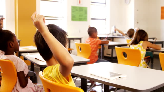 Niños-de-la-escuela-levantando-la-mano-en-el-aula