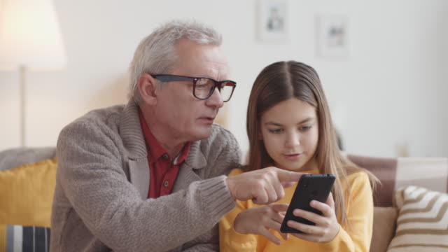 Kaukasischer-Großvater-lehrt-Mädchen,-wie-man-Smartphone-verwendet