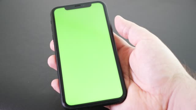Hand-holding-mobile-phone-with-green-screen.-Chroma-key