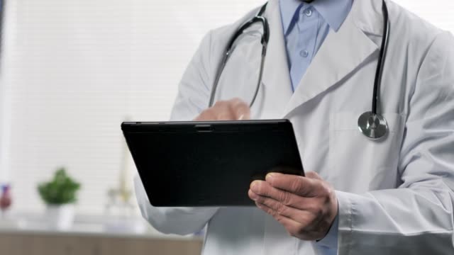 primer-plano-de-un-médico-usando-una-tableta-detrás-de-un-vaso