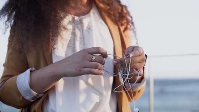 Close-up-of-young-woman's-hands-untangling-tangled-earphones