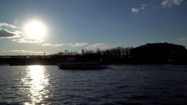 eine-romantische-Aussicht-auf-den-Fluss-bei-Sonnenuntergang-mit-Schiffen-und-Silhouetten-von-Menschen