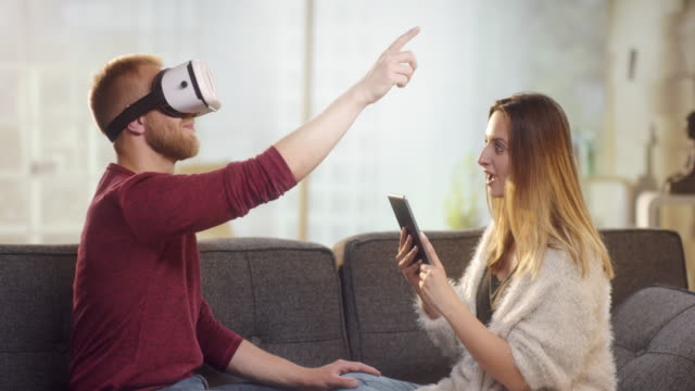 Junge-süße-paar-auf-Couch-mit-VR-zu-spielen-und-Spaß-haben