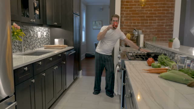 Attractive-man-finishing-his-coffee-leaves-his-kitchen-dancing-with-mobile-phone
