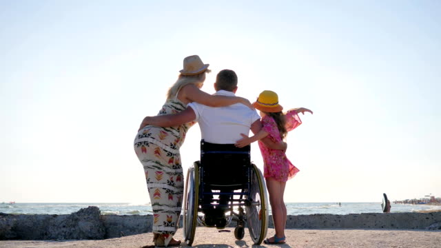 behinderter-Mann-mit-Frau-und-Tochter-auf-Hintergrund-Meer