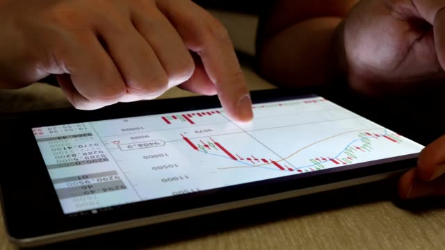 Online-trading.-Man-using-tablet-for-checking-financial-market-stock-information.