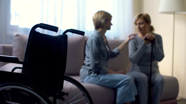 Fürsorgliche-Tochter-im-Gespräch-mit-behinderten-älteren-Mutter-zu-Hause,-rehabilitation