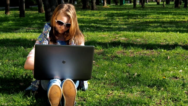 Mädchen-an-einem-sonnigen-Tag-in-einem-Park-mit-einem-laptop