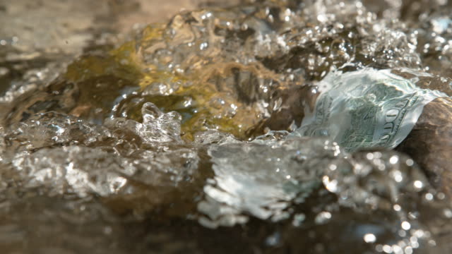 Makro:-kristallklare-Wasser-fließt-über-die-hundert-Dollar-Rechnung