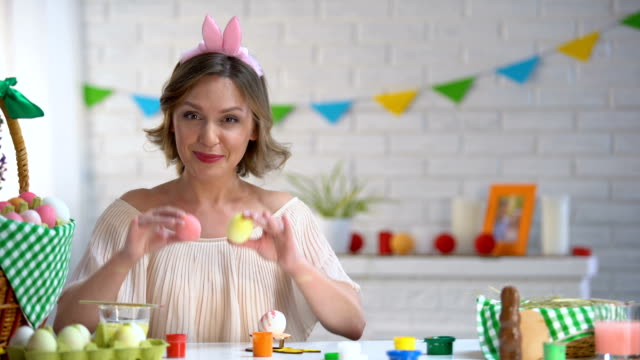 Smiling-woman-having-fun-holding-colorful-Easter-eggs-near-her-eyes,-joke