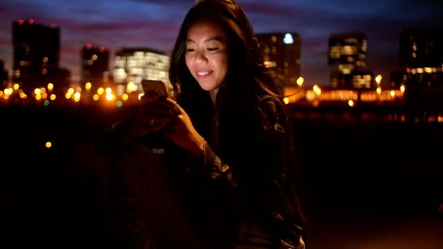 Glücklich-Hipster-Asiatin-Textnachrichten-im-Stadt-bei-Nacht