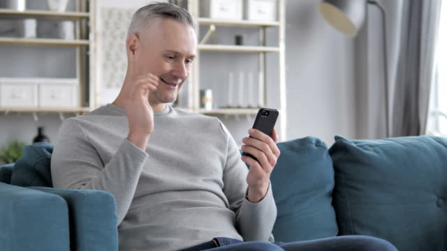 Online-Video-Chat-auf-Smartphone-durch-entspannende-graue-Haare-Mann