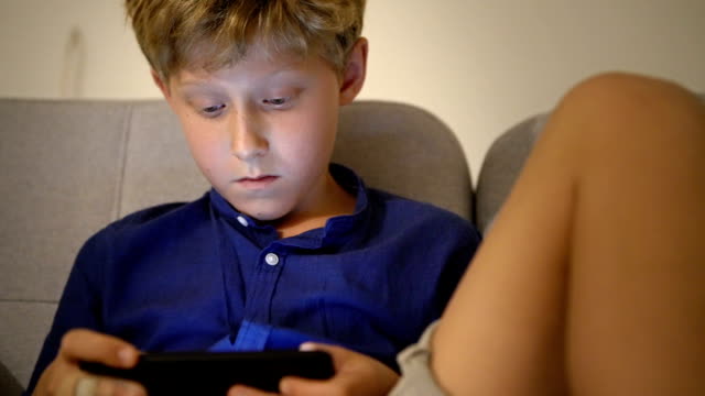Little-boy-playing-the-online-game-using-the-mobile-smartphone-gadget-device