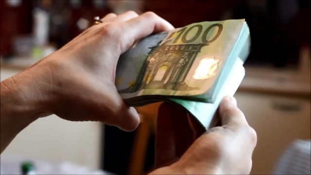 hands-handling-a-wad-of-hundred-euro-bills.