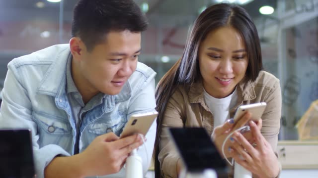 Pareja-asiática-eligiendo-smartphones-para-comprar