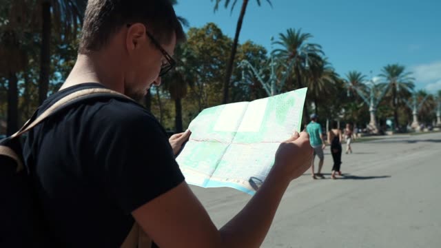 Man-is-examining-map-of-city-transport,-looking-around-on-street