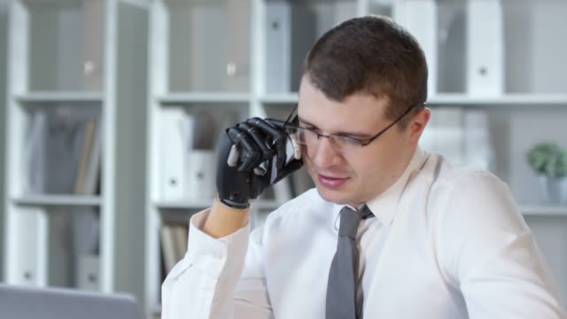 Businessman-with-Prosthetic-Arm-Talking-on-Phone-in-Office