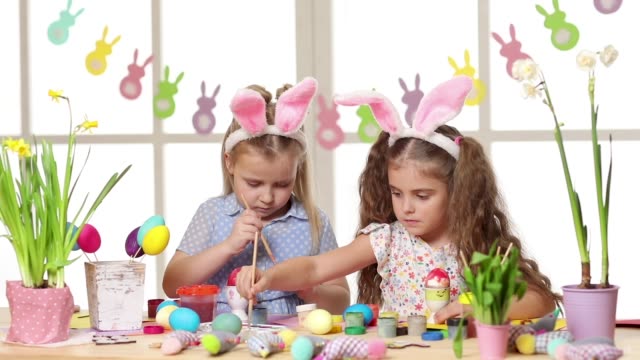 Happy-children-wearing-bunny-ears-painting-eggs-on-Easter-day.