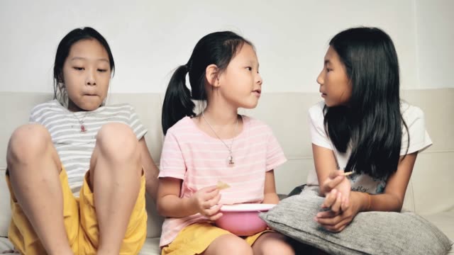 Glückliches-asiatisches-Mädchen-essen-Chips-mit-der-Familie-und-sprechen-zusammen-zu-Hause-in-der-Nacht.