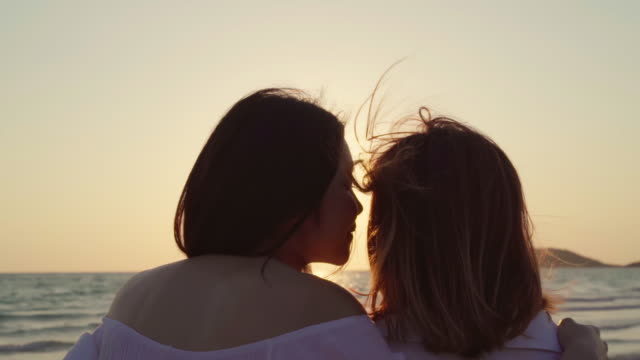 Slow-motion---Young-Asian-lesbian-couple-kissing-near-beach.-Beautiful-women-lgbt-happy-relax-enjoy-love-and-romantic-moment-when-sunset-in-evening.-Lifestyle-lesbian-couple-travel-on-beach-concept.
