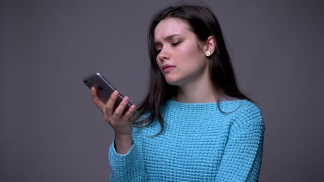 Nahaufnahme-von-jungen-hübschen-Brünette-weibliche-SMS-auf-dem-Telefon-mit-Hintergrund-isoliert-auf-grau
