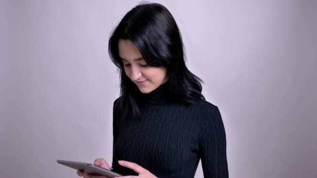 Closeup-shoot-of-young-pretty-caucasian-female-with-black-hair-using-the-tablet-and-smiling