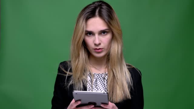 Closeup-shoot-of-young-attractive-hipster-caucasian-female-using-the-tablet-and-looking-at-camera-with-background-isolated-on-green