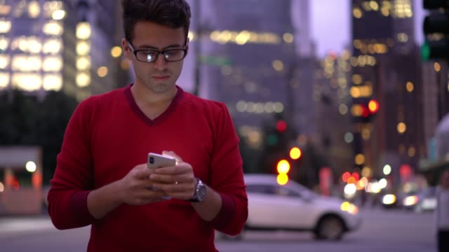 Fröhlicher-männlicher-Teenager-in-Brille-genießen-Smartphone-Kommunikation-mit-besten-Freund-während-der-Zeit-für-das-Gehen-im-Freien