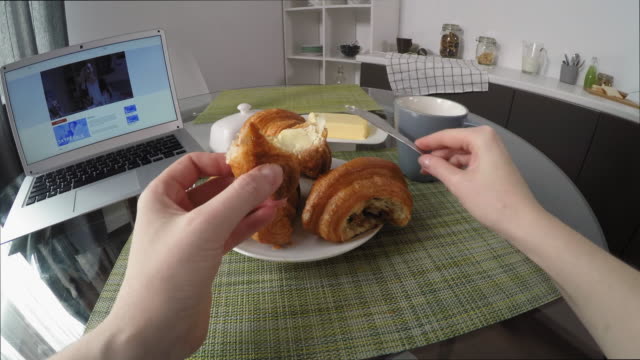 POV-von-Frau-Essen-Croissant-und-Watching-Serie-auf-Laptop
