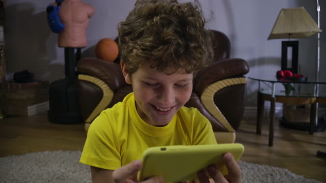 Close-up-face-of-Caucasian-curly-haired-boy-watching-comedy-show-at-smartphone-screen.-Joyful-kid-laughing.-Generation-Z,-social-media,-internet,-modern-technologies.-Cinema-4k-ProRes-HQ.