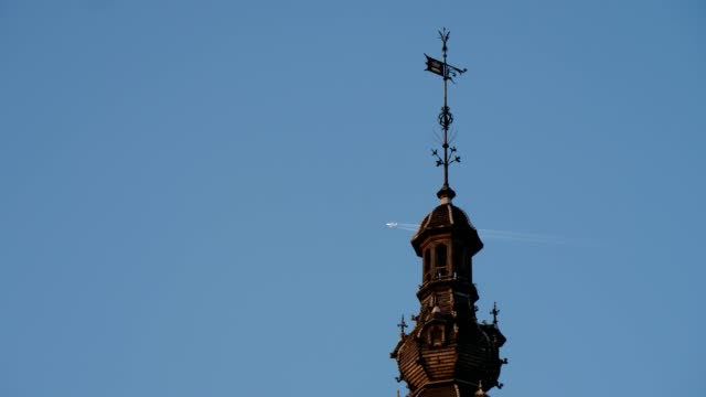 Spire-of-ancient-building-and-flying-airplane-in-the-blue-air-in-Brussels-in-slo-mo