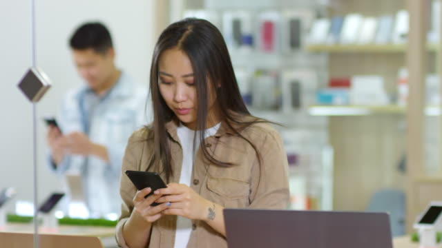 Clientes-asiáticos-que-usan-teléfonos-inteligentes-en-la-tienda