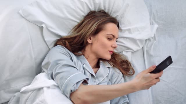Sleeping-woman-lying-on-bed-awaking-from-mobile-call-at-morning.-Close-up-shot-on-4k-RED-camera