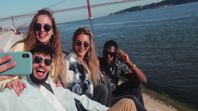 Close-up-multi-ethnic-friends-taking-selfie-with-smartphone-by-riverside
