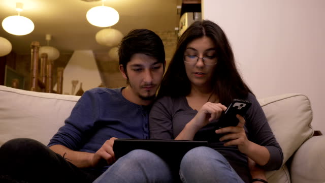 Jóvenes-en-el-hogar-del-hombre-utilizando-el-tablet-pc-y-mujer-teléfono-inteligente-compras-y-pagar-en-línea-con-bitcoin-y-cryptocurrencies