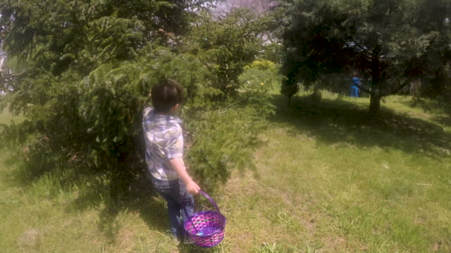 Enthusiastic-young-boy-running-and-finding-Easter-eggs-on-a-Easter-egg-hunt