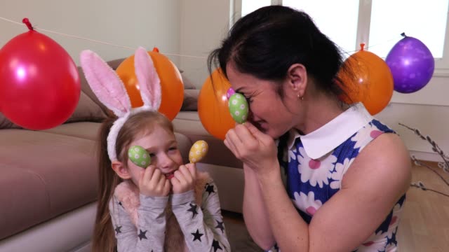 Glückliche-Mutter-und-Tochter-halten-Ostern-Eiern-in-der-Nähe-von-Augen