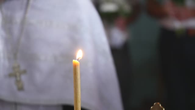 The-Candle-Burns-in-a-church.-priest-in-the-background.-selective-focus